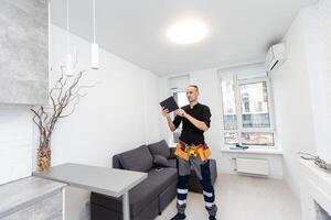 Worker with tablet computer checking alarm system indoors photo