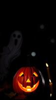 Jack-o'-lantern glowing in the dark with ghost and candles photo