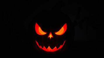 glowing jack-o'-lantern with an evil grin stares into the darkness photo