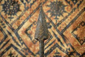 Antique spearhead against ornate background photo