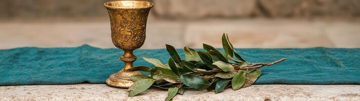 ornate golden chalice with olive branch on teal fabric photo