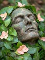 serene stone face surrounded by lush greenery and delicate flowers photo