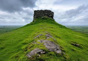 Mysterious stone structure on grassy hill with cloudy sky photo