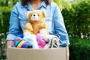 Volunteer collect cloth and doll in cardboard box to donate. photo