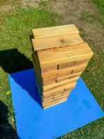 Outdoor wooden Jenga tower on a blue platform, ready for a fun garden game. High quality photo