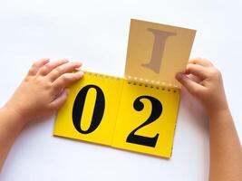 Childs hands flipping educational flashcards with numbers and letters on bright yellow background photo
