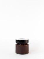 Minimalist display of small brown glass jar with black lid on white background photo