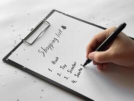 Creating a festive holiday shopping list with handwritten details on a clipboard photo