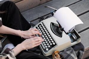 hands of a woman writer on the keyboard of a typewriter on the background of a wooden floor, copy space. photo