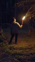 A mysterious figure is seen holding a torch while wandering in a dark and eerie forest video