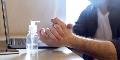 Unrecognizable Man Using Sanitizer Disinfecting Hands For Virus Protection Before Work On Laptop At Home. Panorama, Cropped photo