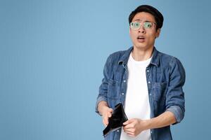 Poverty and absence of money. Unemployed sad asian guy showing empty wallet, looking at camera, standing over light studio background with free space photo