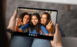 Three friends happily pose for a selfie, enjoying a virtual meeting from their cozy living room. Their smiles convey joy and friendship while they connect online. photo