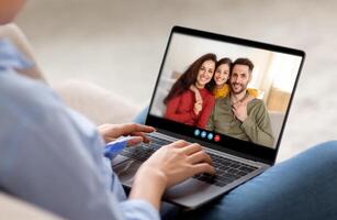 A person is engaged in a call with family members, smiling warmly while seated in a comfortable living area, creating a moment of connection and joy. photo