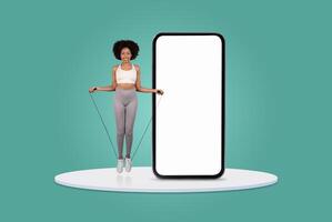 A woman jumps rope while smiling, showcasing her fitness routine beside a large blank smartphone display. The bright, minimalist background emphasizes her activity and enthusiasm for exercise. photo
