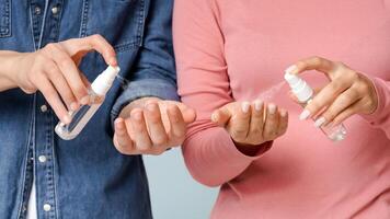 Cropped image of unrecognizable man and woman applying hand sanitizers, spraying droplets, closeup photo