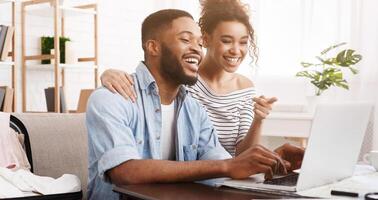 African-american couple searching tour online on laptop, preparing for holidays photo