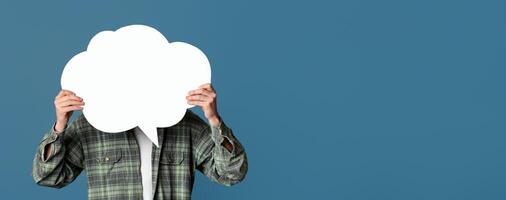 Young guy covering his face with speech bubble on turquoise background, space for design photo