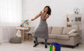 Spring cleaning may be fun. African-american girl using mop like microphone photo