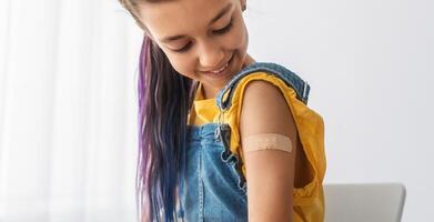 Healthcare And Inoculation Concept. Portrait Of Smiling Teen Patient Showing Vaccinated Arm With Plaster On Shoulder After Coronavirus Vaccination, Looking At Hand. Antiviral Vaccine, Banner, Panorama photo