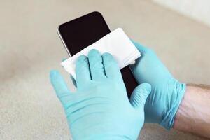 Man Sterilizing Mobile Phone Before Use At Home. Gadget Hygiene During Coronavirus Pandemic. Panorama, Cropped, Selective Focus photo