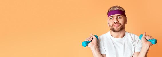 Bored millennial guy doing exercises isolated on yellow background photo