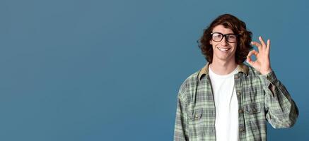 Curly millennial guy showing okay gesture, expressing positivity on turquoise background photo