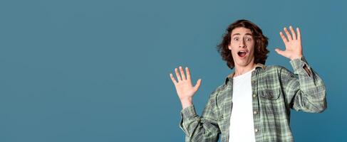 Panic and stress concept. Handsome young guy with frightened facial expression on turquoise background photo