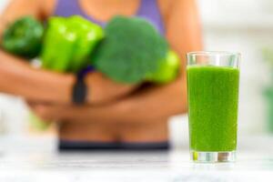Healthy Smoothie. Unrecognizable african woman holding green vegetables, selective focus on blended green juice photo
