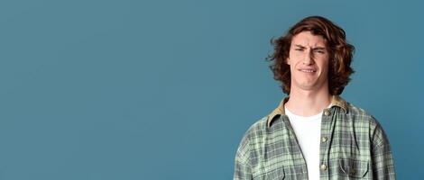 Young guy with disgusted expression on turquoise background photo