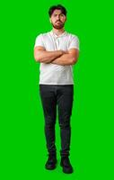 A young man with a beard showing a serious expression against a vibrant green background photo