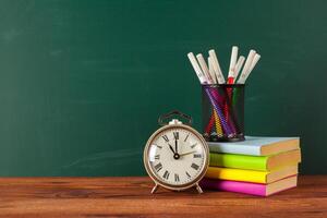 School supplies on a wooden table and blackboard photo