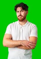 A man with a serious expression stands with crossed arms against a vibrant green background photo