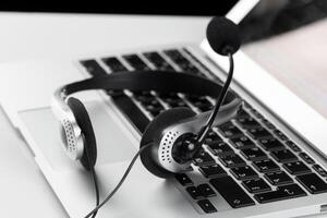 call center support concept. headset on keyboard computer laptop photo