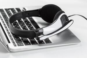 call center support concept. headset on keyboard computer laptop photo