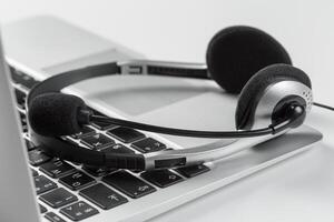 call center support concept. headset on keyboard computer laptop photo