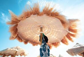 View from below of beautiful thatched umbrellas on the beach. photo