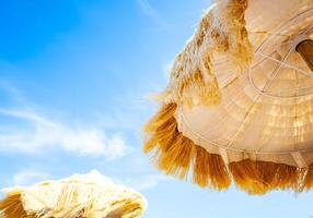View from below of beautiful thatched umbrellas on the beach. photo