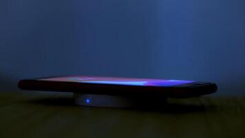 Wireless induction charger base for mobile phone. Moonlight scene while a smartphone is placed on the dock for charging. photo