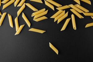 Raw pasta penne rigate with copy space on black background. photo