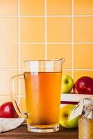 Apple cider in a glass jug on a wooden table photo