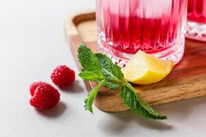 Raspberry cocktail with ice in a glass on a light background photo