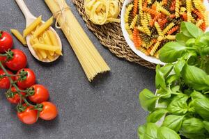 Raw pasta fusilli in bowl with spaghetti, tagliatelle, penne. photo