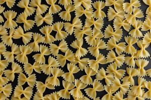 Raw pasta farfalle pattern on black background. photo