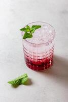Cocktail with ice in a glass on a light background photo