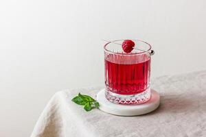 Cocktail with raspberry in a glass on a marble stand photo