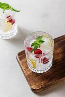 Raspberry cocktails with ice in a glass on a light background photo