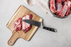 Uncooked beef ribs on wooden cutting board with knife photo