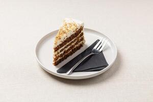 A piece of carrot pie on a white plate. A delicious dessert on the table with a beige tablecloth. photo