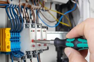 Hand Using Screwdriver on Electrical Terminal Block photo